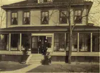 B&W photo of a building with people standing in front of it.