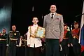 A young male cadet receiving an award from a member of the school staff.