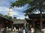 A temple in the mountains with a white stupa in the background