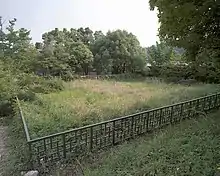 Historic site covered by grass and surrounded by a fence