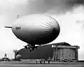 U.S. Navy blimp in front of one of Tustin's massive blimp hangars in 1943