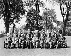 A posed group of men, taken out of doors, with one row seated, one standing