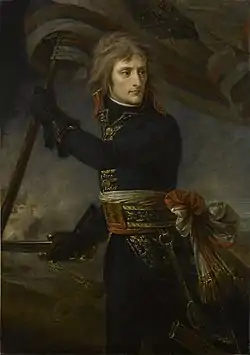 A three-quarter-length depiction of Bonaparte, with black tunic and leather gloves, holding a standard and sword, turning backwards to look at his troops