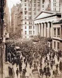 Perhaps a thousand men, mostly in dark suits and bowler hats, swarm outside a building. There is a 20-foot statue of a man in front of the building and the men have crowded atop the base of the statue.