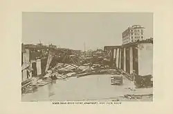 An image showing devastated apartment buildings, with debris blocking the road