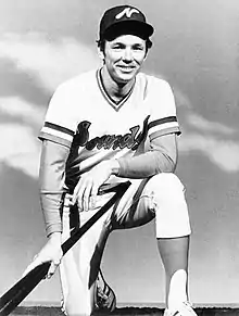 A black and white photograph of a man kneeling wearing a white baseball uniform with "Sounds" written on the front