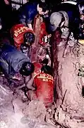 Rescue workers wearing orange uniforms can be seen crouching.