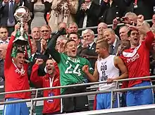 Players celebrating, one of whom is holding aloft a trophy