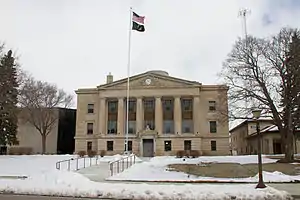 A three-story domed building with a Neoclassical façade fronting a snowy plaza