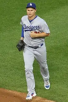 A man in a gray baseball uniform and blue cap