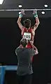 After the gymnast jumped up, the coach assists the gymnast by lifting him up