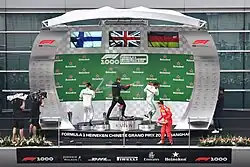 Three men in racing overalls spraying champagne on a podium after the 2019 Chinese Grand Prix