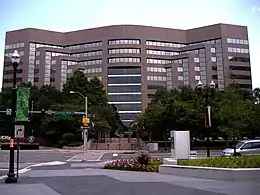 Brown metal and glass building, curved at the center and angled at the sides