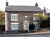 A two-storey brick house with stone dressings and a pedimented doorway