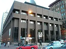 A gray brutalist building on a street corner in an urban environment