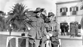 an outdoors photograph of two soldiers standing near a table