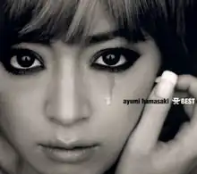 A dark, black-and-white up-close shot of Ayumi Hamasaki looking into the camera, with a teardrop trickling down one cheek.