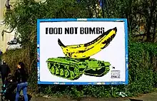 A banana stands atop a green war machine. Atop is the title "food not bombs". In the bottom right corner, green font reads "the government spends billions on war while millions go hungry."