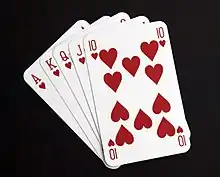 Five playing cards – the ace, king, queen, jack and ten of hearts – spread out in a fan.