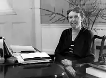 Female civilian sitting at desk with hands crossed