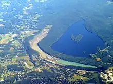 A view from an aircraft of a long and relatively narrow quarry, with a large lake to its right. Below and to the left are houses.