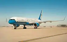 C-32 taxiing on dusty airport tarmac, showing "United States of America" lettering and tail with U.S. flag.