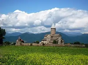 Church from far, field in front, hills in the back