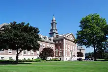 An ornate three-story brick building with a pedimented front section and tall gray cupola