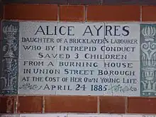 A tablet formed of six standard sized tiles, bordered by green flowers in the style of the Arts and Crafts movement