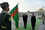 A color guard lowering the national flag in the present arms position.