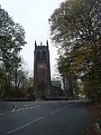 A tower seen from a distance, with a clock face and pinnacles