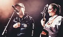 A man and a girl play guitar together on stage