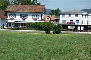 White two story building with arched roof and a wooden shelter