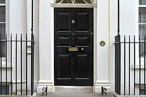 A white building with a black door, with the number eleven on the door