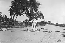 Black and white photo of a man standing among bodies lying on the ground