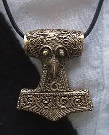 A metal hammer, worn as a pendant around an individual's neck