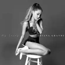 Ariana Grande kneeling on a stool, with her head resting on her hand