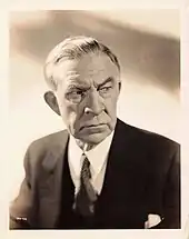 Black and white portrait photo of a white man wearing a suit and tie.