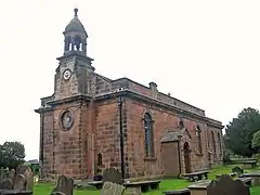 A Neoclassical stone church with a small bell tower and cupola