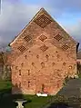 Gable end of a brick barn with ventilation holes built into the brickwork.