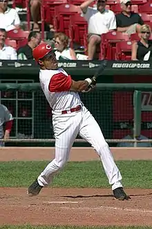 A man in a white baseball uniform and red undersleeves and cap