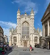 Yellow stone building with large arched windows and a tower.