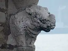 An eroded statue shaped as the front quarters of a rhinoceros. The background is water.