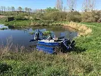 This amphibious boat 'amphi king' is used for maintaining waterways, like freeing them from water plants