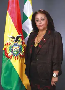 Official portrait of Betty Tejada flanked to the left by the Bolivian tricolor and the Wiphala.