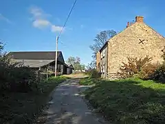 A narrow country road with a farm on the right, and a barn on the left