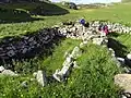 People standing next to Blackhouse ruins on Pabbay