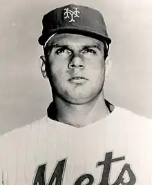 A man man in a light baseball jersey with "Mets" across the chest and a dark cap