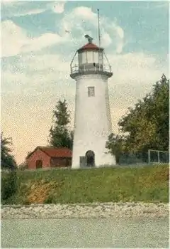 The top half of the background is mostly clear sky, the lower part consisting of a forest. Above the forest canopy rises a cylindrical white tower tapered to its peak, with a base sitting on a grassy field. Two small windows are visible, one roughly at one-third the height of the tower on the right, the other two-thirds up on the left. A cornice in three steps tops the building. Just below the cornice, the tower exhibits some weathering damage in patches.