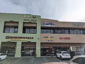 Two levels of storefronts at a strip mall.